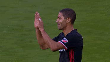 Sports gif. Saborio of the D.C. United soccer club high-fives several teammates as they congratulate him.