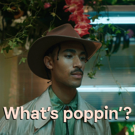 Video gif. A man with dreadlocks under a brown cowboy hat holds a sprig of grass in his mouth. He smirks and nods to someone offscreen. Text, "What's poppin'?"