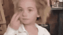 Video gif. Young girl with pigtails looking at us with wide eyes, fore and middle finger in formation pointing at her eyes and then us, backing away, disappears behind a corner.