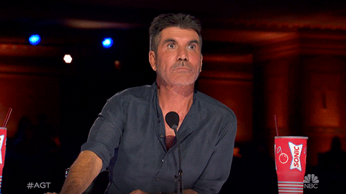 Reality TV gif. We zoom in on Simon Cowell from America’s Got Talent, his eyes wide with shock.