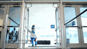 Sports gif. Miami Marlins mascot runs in through a doorway, chased by several male and female cheerleaders, pausing for a moment after entering to do a suggestive pelvic thrust.