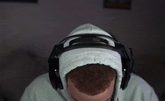 Video gif. A man wearing headphones and playing video games looks at us and says, “Damn that’s crazy bro.”