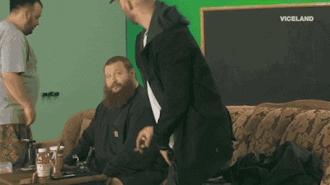 Photo gif. We zoom in on a bearded Action Bronson as a lime green alien face covers his. Text, "Welcome back."