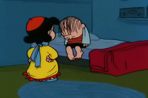 Peanuts gif. Linus sits on the edge of his bed and then falls over, asleep, as Lucy pulls the blanket over him and walks away.