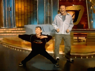 Video gif. Young boy and a man dance on a stage of a tv show. The man moves his knees in and out and his arms around with a big smile on his face. The boy dances around clapping, pointing up, and sticking his legs out. Text, “Yay!”