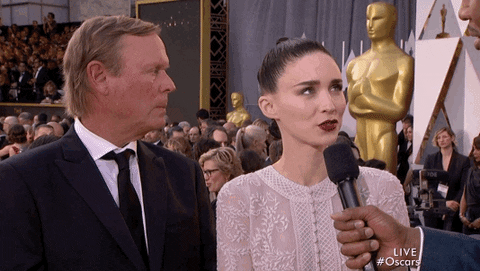 Celebrity gif. Rooney Mara is being interviewed at the Red Carpet for the Oscars when she slightly frowns and glances away from the interviewer, as if she made a small mistake.