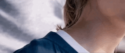 Movie gif. Intimate cropped shot of a person leaning in from behind to delicately kiss someone's neck.