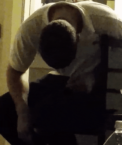 Video gif. A man sits slumped over, passed out in a chair. He tips forward and splays out on the floor. 