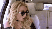 Celebrity gif. Britney Spears's hands cover her dropped jaw as if in shock as she sits near someone in a car. 