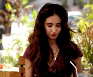 TV gif. Gabrielle Ruiz as Valencia in Crazy Ex-Girlfriend does a two finger salute as she winks with a half smile.
