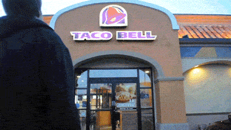 Ad gif. Man struts towards a Taco Bell and grandly swings opens its doors. He looks around him in awe and spreads his arms wide to take in all the glory.
