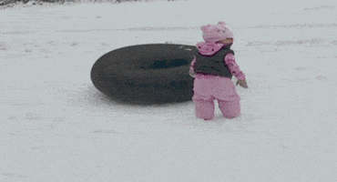 Video gif. A little girl is standing in front of a sledding tube when all of a sudden, a golden retriever army crawls by with their legs fully extended in a sploot.  Both the little girl and her father and shocked at the sight.