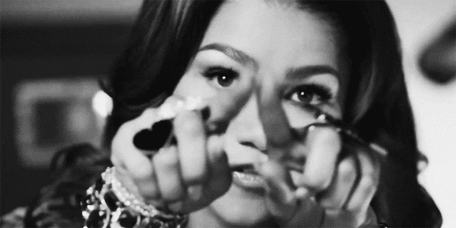 Celebrity gif. Zendaya draws a heart in the air with her hands. 