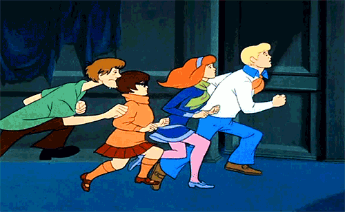 Video gif. Fred, Daphne, Velma, Shaggy, and Scooby run frantically away from something in the dark.