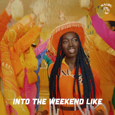 Ad gif. For Malibu Rum. A woman wearing all orange smiles and dances through a crowd of people wearing bright colors and holding up their glasses. Text, "Into the weekend like."