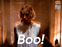 Sponsored gif. Woman screams in fear as Freddy Krueger from Nightmare on Elm Street pops up behind her and grabs her. In the upper right corner is the AMC Fear Fest logo. Text reads, “Boo!”