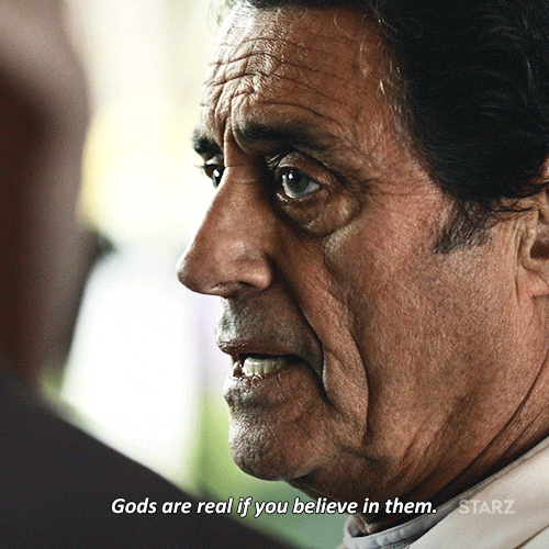 TV gif. Ian McShane as Mr. Wednesday in American Gods looks at someone dead in the eye and says, "Gods are real if you believe in them" before looking away.