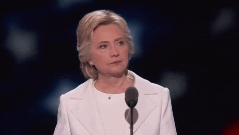 Politics gif. Hillary Clinton shakes her head judgmentally, standing at the podium at the Democratic National Convention in 2016.