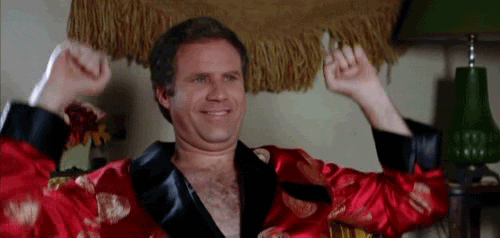 Movie gif. Will Ferrell as Chazz in "Wedding Crashers" wears a red satin robe with black cuffs and lapel, pumps his arms up and down and smiles.