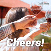 Sponsored gif. Three people clink their glasses of red wine together as they sit outside on a California patio. Text reads, “Cheers!”