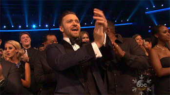 Celebrity gif. Justin Timberlake in a classy tuxedo at the AMAs claps and yells enthusiastically in the crowd, furrowing his brow expressively like he's intensely happy about this moment.