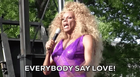 Celebrity gif. RuPaul is on stage at a Pride event and they raise their hand to address the crowd, saying, "Everyone say love!"