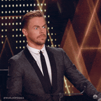 Reality TV gif. Derek Hough from World of Dance freezes and gazes ahead with raised eyebrows like he's in shock and awe. 