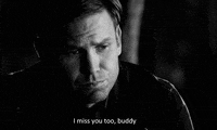 Black and white video gif. Man looks down with sorrowful eyes and says, “I miss you too, buddy.”