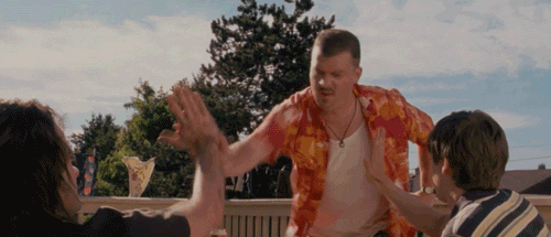 Movie gif. Danny Mcbride as Rico in Hot Rod Leans forward and high fives two people in front of him with a determined look on his face. 