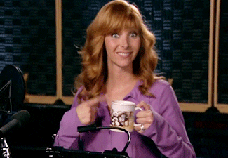 TV gif. Lisa Kudrow as Valerie on The Comeback. She looks eager as she beckons us forward and sips on a mug of coffee.