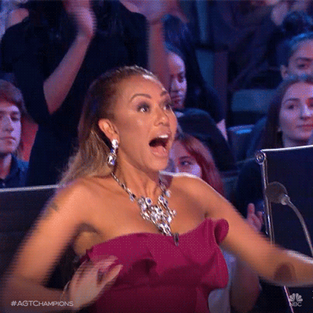 Reality TV gif. Mel B as a judge on America's Got Talent. She's overjoyed at watching the contestant and her eyes are wide as she raises her hands above her head to clap.