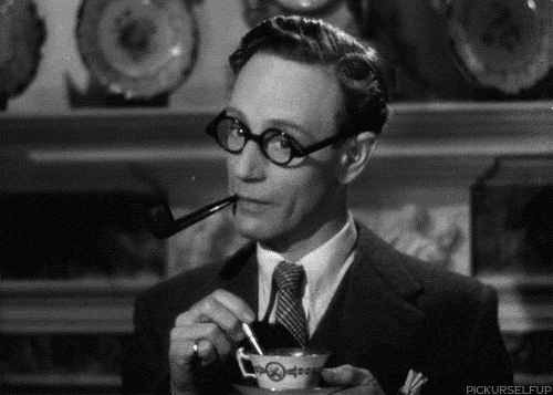 Movie gif. Leslie Howard as Professor Henry Higgins in Pygmalion, decked out in bold glasses, pipe in his mouth, stirs his tea, nodding and listening.