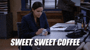 TV gif. Melissa Fumero as Amy Santiago on Brooklyn Nine Nine sitting at her desk and opening the lid of her coffee. Text, "Sweet, sweet coffee."