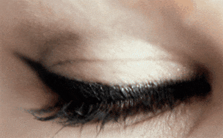 Video gif. A beautiful blue eye lined with cateye makeup blinks and reveals a gorgeous blue iris. 