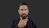 Video gif. Jimmy Lavalle from The Album Leaf strokes his beard stares at us as he thinks.