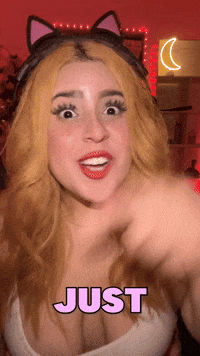 Video gif. Shalymar Rivera Gonzalez wears cat ears as she points at us with wide eyes and says matter-of-factly, "Just because I play the piano," which appears as text. She wiggles her fingers to replicate playing the piano. 