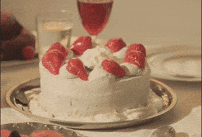 Video gif. The words "happy anniversary" appear over a white-frosted cake decorated with strawberries, which suddenly gets stepped on by a person wearing clear pleaser heels.