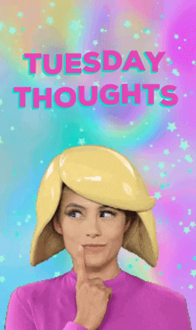 Video gif. A woman wearing a hat shaped like the emoji woman's hair and a pink shirt is replicating the thinking woman emoji. She has a finger to her lips and she looks side to side, contemplating. Text, "Tuesday Thoughts."