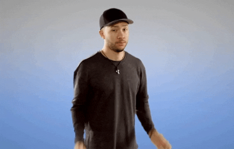 Video gif. A confused man in a baseball cap shrugs, holding up his hands. Text, “IDK?”