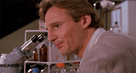 Movie gif. Liam Neeson as Peyton in Darkman, turns from his microscope to look at someone off screen with a look of confusion and unhappiness, saying "Why? Why? Why? Why?"