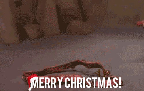 Cartoon gif. In a scene from Rudolph the Red-Nosed Reindeer, a stop-motion Rudolph picks up a set of jingly reins from the floor with his nose and proudly puts them on, but he's not exactly wearing them right. The text "Merry Christmas!" is wearing a Santa hat.