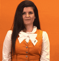 Video gif. A woman looks at us and crosses her fingers excitedly, smiling broadly and hopefully looking at us.