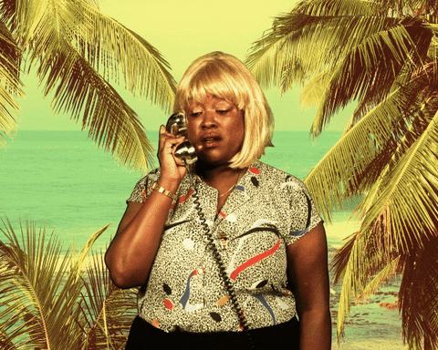 Video gif. Tashi Condelee standing in front of a fake beach scene, talking on a silver telephone, pulling it from her ear, and looking excited. Text, "yea, yea, yea, it's Friiiiday."