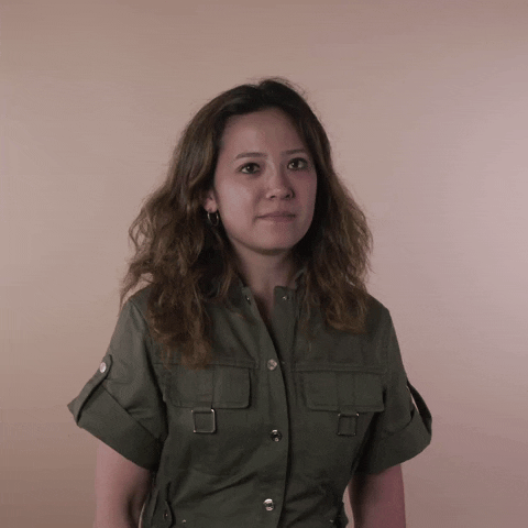 Reaction gif. A Disabled Vietnamese-American woman hemorrhagic stroke survivor with left-sided hemiplegia, brown sun-bleached hair styled in waves rolls her eyes with a toss of her head, pouting slightly.