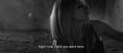 Music video gif. Avril Lavigne in her music video for Wish You Were Here. She's sitting on the floor and sadly sings, "Right now, I wish you were here."