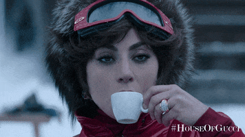 Movie gif. Lady Gaga as Patrizia in House of Gucci. She's wearing ski gear and she takes a sip of her espresso as she stands in the snow.