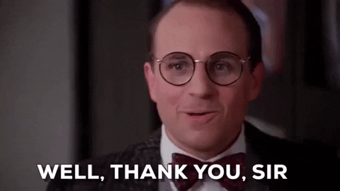 TV gif. Eliot Loudermilk as Bobcat Goldthwait from Scrooged wearing large round glasses and a tuxedo, smiles as he speaks to us with a hint of timidity. Text, "Well, thank you sir."
