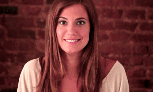 TV gif. Allison Williams as Marnie in Girls. She smiles cutely and raises show us both her fingers crossed as she looks at us hopefully and expectantly.
