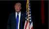 Political gif. Donald Trump poses onstage next to an American flag as if it were a person, crouching slightly while pointing at it and raising a thumbs up.