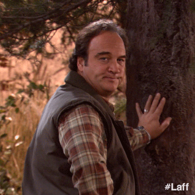 TV gif. Comedic actor Jim Belushi in According to Jim stands with his hand against the trunk of a tree. He whips his face toward the camera in utter shock with his eyes wide and jaw dropped as the shot zooms in on his expression.